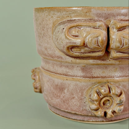 Close up view of a sculptural ceramic vessel with a mottled pink glaze